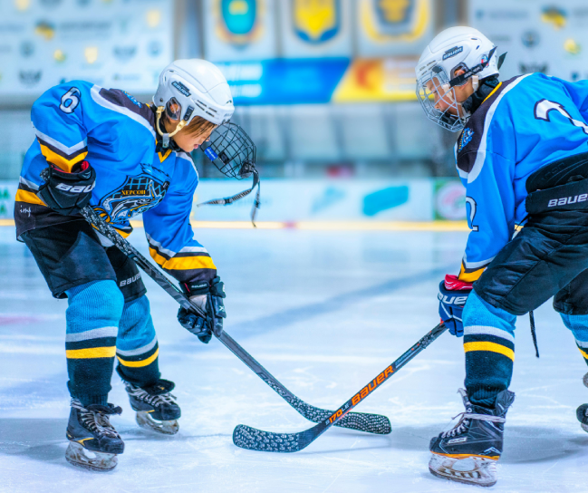 Two young men playing a game of ice hockey.
