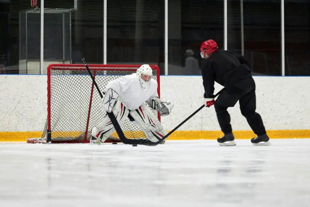A man playing hockey on the ice with another goalie.