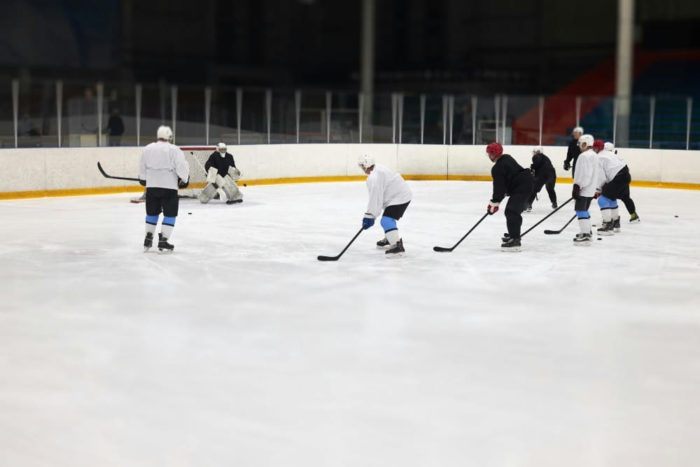 A group of people playing hockey on an ice rink.